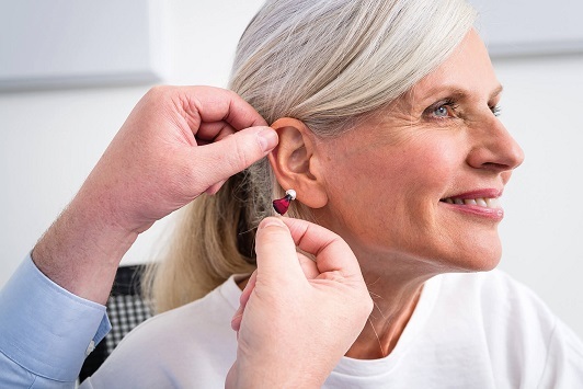 Ältere Frau bekommt Hörgerät eingesetzt, Hörakustiker berät zum modernen Hörsystem.